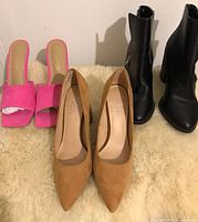 Five pairs of women's shoes lined up including pink open-toe slides, khaki heels, pink stilettos, and two pairs of black ankle booties.