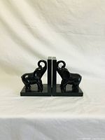 Front view of the pair of black wooden elephant bookends side by side showing their detail and finish.