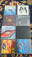 Front view of 8 classic rock CD jewel case covers showing Aerosmith, Bon Jovi, AC/DC, Guns N' Roses albums
