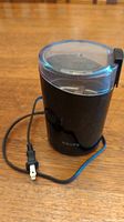 Full view of Krups black electric coffee grinder with transparent lid and attached power cord with plug.
