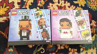 Two unopened Lego BrickHeadz boxes: 40383 Groom on the left (255 pcs) and 40384 Bride on the right (306 pcs) sitting on a colorful patterned carpet.