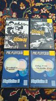 Four PS2 games arranged on a patterned carpet: two in original cases (The Getaway and The Getaway Black Monday) with cover art, two discs in Pre-Played blue generic cases labeled Tony Hawk's Pro Skater 4 and Syphon Filter The Omega Strain.