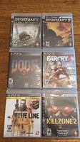 Photo showing the 6 PS3 game cases with visible cover artwork for Resistance Fall of Man, Resistance 2, Doom 3, Farcry 3, Spec Ops The Line, and Killzone 2.