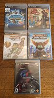 Five PS3 game cases neatly arranged, showing titles from Ratchet and Clank, Jak and Daxter Collection, PlayStation All Stars Battle Royale and Gran Turismo 5.