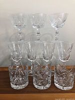 Group photo showing all 11 glasses arranged in three rows by type and size on a wooden surface, highlighting the crystal cut pattern and clarity.