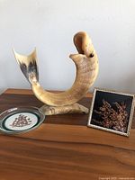 Three items displayed on wooden surface: handcrafted glass coaster with Heather, vintage Heather sprig frame, bone carved fish figurine.