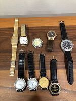 All nine watches displayed on a wooden surface, showing a variety of bands and face styles.
