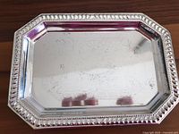 Small silver-colored metal tray with octagonal edges and patterned border, scratched surface visible