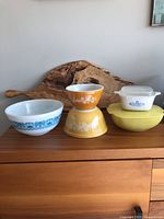 Photo of all five bowls and casserole dish with lids on wooden sideboard, showing size and color variety.