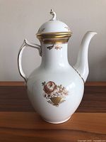 Side view of the Royal Copenhagen coffee pot showing its rounded shape, floral and gold decorative pattern, and curved handle and spout.