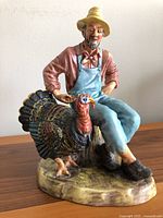 Full view of the Royal Doulton figurine showing the seated farmer with a turkey on a textured base, displaying the overall size and color.