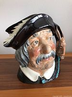 Close-up front view of the Royal Doulton Toby mug depicting Sancho Panca, showing detailed hand-painted face with mustache, rosy cheeks, and feathered hat.