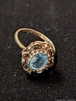 Top view of 925 sterling silver ring with central oval aquamarine stone and ornate surrounding beadwork and filigree details on black background.