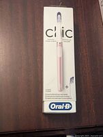 Front view of the Oral-B Clic electric toothbrush box showing the product name, pink toothbrush image, and brand logo.
