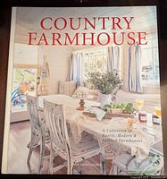 Front cover of Country Farmhouse book showing a bright farmhouse interior with rustic wooden table and chairs, windows with white and blue curtains, and decorative items.