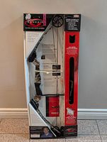 Photo of the Genesis compound bow in retail packaging, showing the bow with pulleys and camo handles.