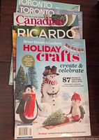 Photo showing stack of 5 magazines with Better Homes and Gardens Holiday Crafts 2022 on top, featuring snowman and penguins craft project cover.