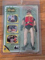 Front view of the unopened Robin action figure in its original packaging showing branding and character image.