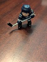 Front view of a small plastic hockey player figurine in Toronto Maple Leafs blue and white uniform, holding a stick and ready to play.