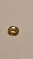 Oval faceted yellow sapphire on white background showing color and cut