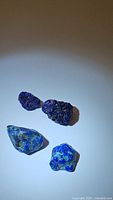 Four natural azurite stones including two rough crystalline and two polished mineral specimens on white background