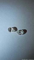 Close-up photo of two pear-shaped colorless zircon gemstones on a white background with light shadows.