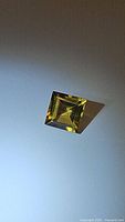 Natural square cut golden citrine gemstone shown from an angle on a white background to highlight color and cut.