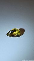 Close-up image of pear-shaped faceted golden citrine gemstone showing the vibrant yellow color and clarity.