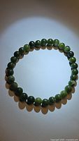 Natural green jade beaded bracelet laid in a circle showing round polished beads.
