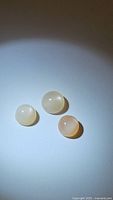 Three round cabochon moonstones viewed from above showing size and color variation.