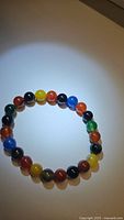 Natural rainbow agate stretchy bracelet arranged in a circle on a white surface, showing multicolored polished beads.