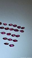 Top view of 26 marquis and pear cut rubies, showing color and clarity under lighting.