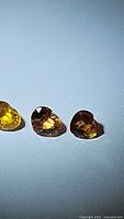 Three heart-shaped natural sapphires in varying golden-yellow to brown hues shown under light to highlight facets and clarity.