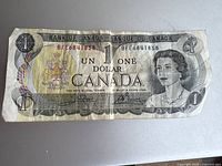 Front side of 1973 Canadian 1 Dollar banknote showing Queen Elizabeth II portrait, coat of arms, bilingual text and serial numbers.