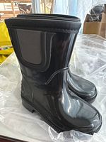 Side view of black shiny rubber boots with mid-calf height and side panel detail