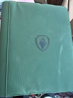 Front view of green canvas portfolio cover with embossed flame shield logo