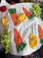 Front side of the snuffle mat showing colorful felt carrots and foliage on a white cotton fabric base.