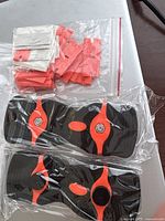 Two black and orange razor blade scrapers packed in clear plastic wrap, along with a plastic bag containing multiple orange plastic razor blade holders.