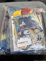 Sealed clear plastic packaging containing the multicolor character-themed party supplies including plates, cups, napkins, straws, and character stickers.