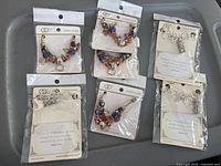 Six individually packaged keychains with multicolor beads or silver charms, paired with inspirational prayer cards containing Bible verses.