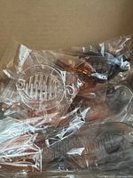 Seven plastic banana hair clips in various shades individually wrapped in clear plastic inside a cardboard box.