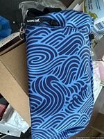 Photo of the blue and navy synthetic flask bag with wave pattern showing its shape and colors.