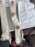 Photo of white and brown over-the-door hook rack parts wrapped in plastic with assembly instructions