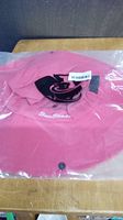 Pink Sun Shade sun hat sealed in original plastic packaging, showing front logo and hat shape.