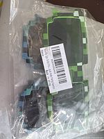 Three pairs of novelty pixelated square sunglasses in green and blue, new in plastic packaging.