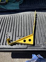 Close-up of a single yellow metal roof jack with rust spots and two mounting holes on flat base.