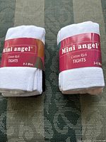 Two pairs of white Mini Angel cotton rich baby tights with size labels 0-3 months and 3-6 months.
