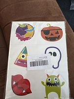 Photo of a temporary tattoo sheet showing colorful Halloween and whimsical designs of bats, pumpkin, ghost, monster, lips, and candy corn.