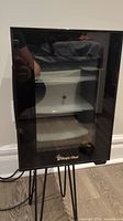 Front view of the Magic Chef black wine cooler showing glass door and logo at the base
