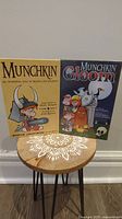 Two board/card games: Munchkin and Munchkin Gloom, boxes standing upright showing cover art of both games.